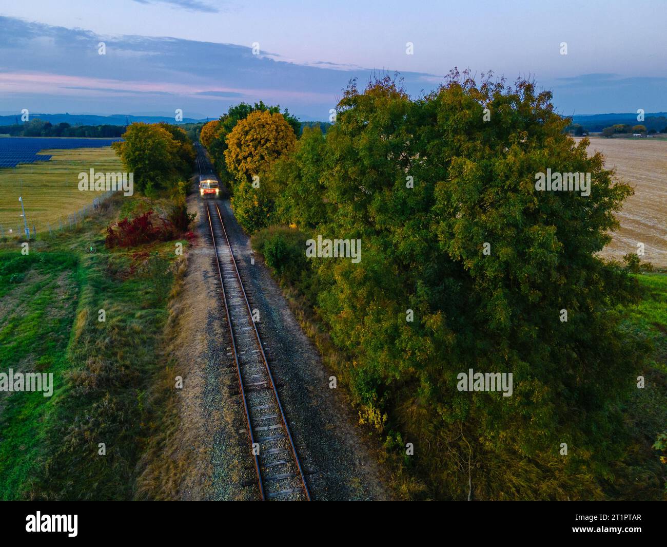 Drone footage of a railway track in an autumn environment with a moving train, Hungary Stock Photo