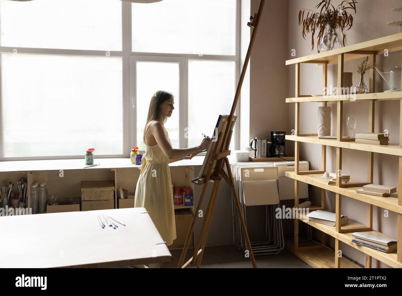In spacious creative workshop young female drawing on easel Stock Photo