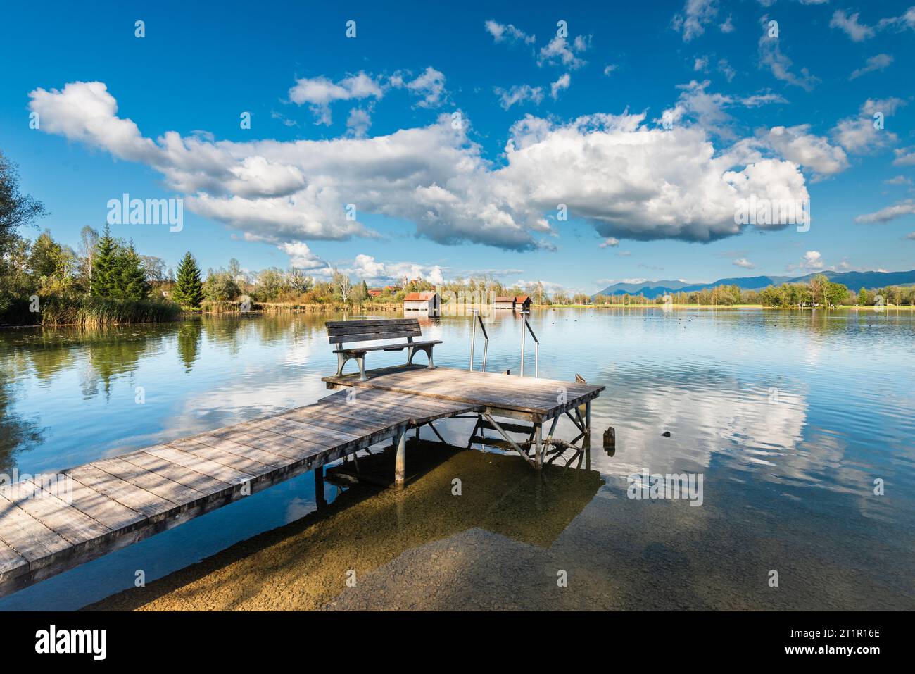 Clouds drifting over a wooden footbridge on the shore of Lake Kochelsee in front of an autumnal mountain landscape and clouds in the sky, Bavaria Stock Photo