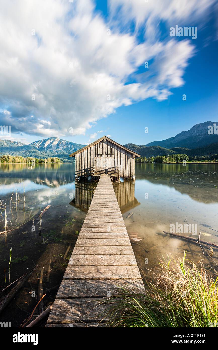 Wooden boathouse on the shore of the Kochelsee in front of the Herzogstand and Jochberg in the evening sun in autumn, Bavaria, Germany Stock Photo