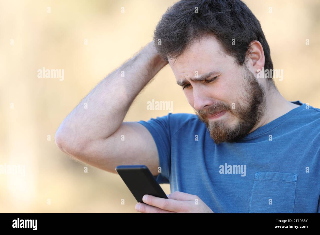 Sad man checking smart phone bad content standing outdoors Stock Photo