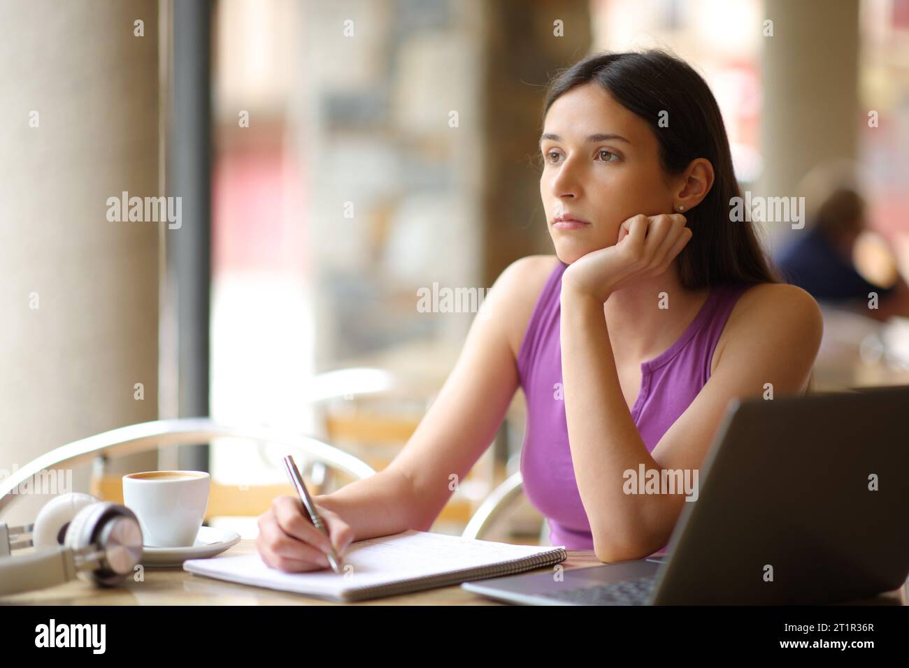 Demotivated student looking away sitting in a restaurant terrace Stock Photo