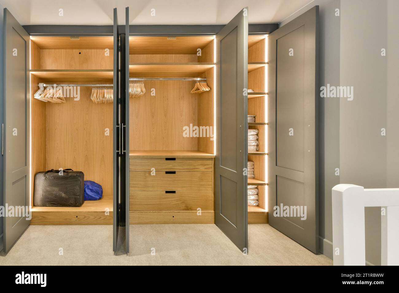 a walk - in closet with clothes hanging on the wall and an open door that leads to a bathroom area Stock Photo