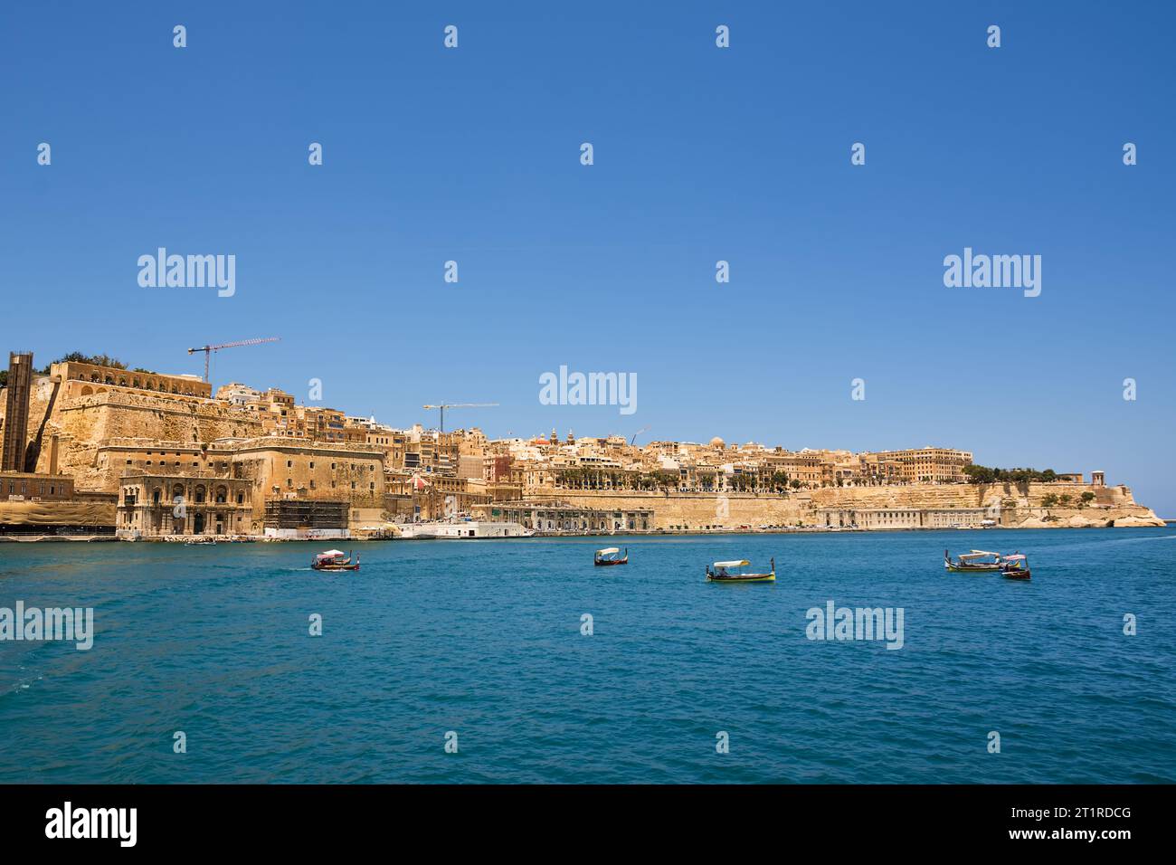 Valletta, Malta - 17 June 2023: Gulf between Valletta and Vittoriosa with passing boats and typical luzzu and Valletta in the background Stock Photo