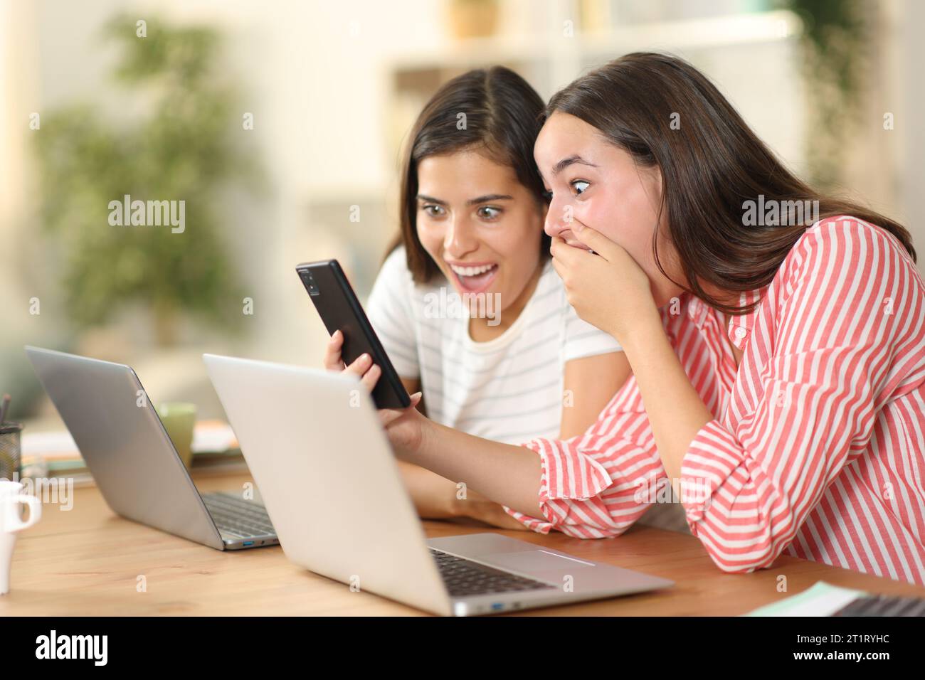 Two amazed tele workers checking phone content at home Stock Photo