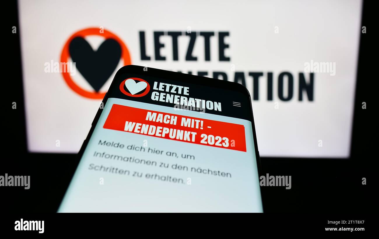 Smartphone with webpage of climate change activist group Letzte Generation (LG) in front of logo. Focus on top-left of phone display. Stock Photo