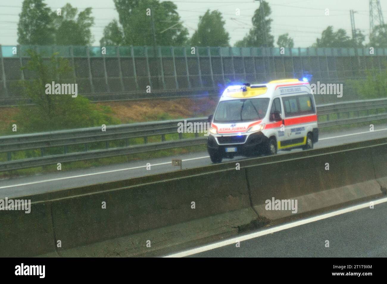 Parma, Italy - May 10, 2023: An Italian ambulance rushes along the highway to provide emergency medical care. Rainy weather, blurry. Stock Photo