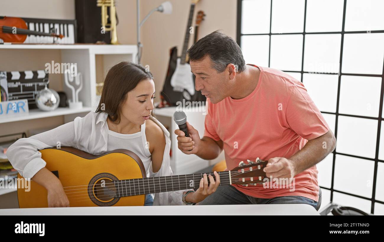 Classic melody in unison, smiling man and woman musicians, confidently playing acoustic guitar, singing soulful song together at spanish music studio Stock Photo