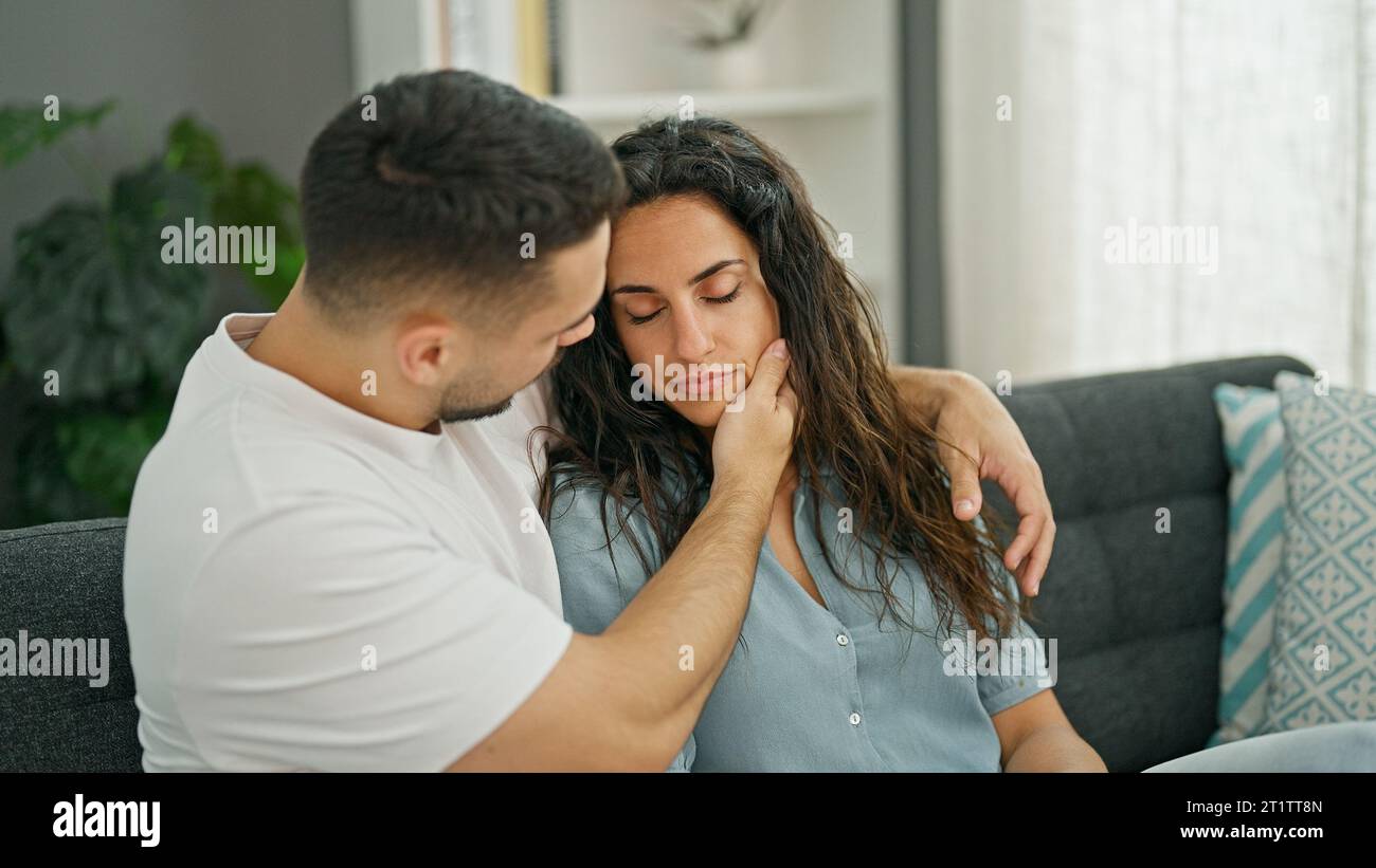 Man and woman couple sitting on sofa consoling girlfriend at home Stock Photo