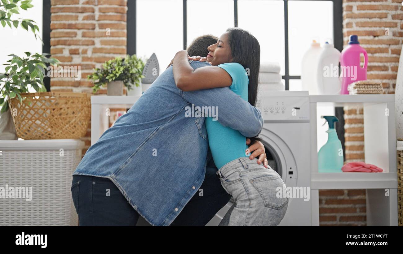 Beautiful couple washing clothes hugging each other at laundry room ...