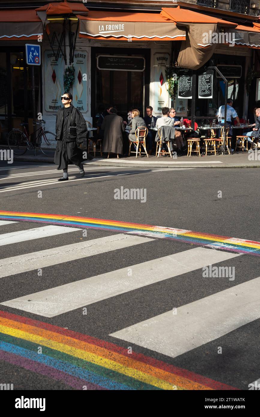 Paris, France - February 21, 2023: Urban scene  in Marais district particularly popular with the LGBT community. Rainbow colored crosswalk; cafe. Stock Photo