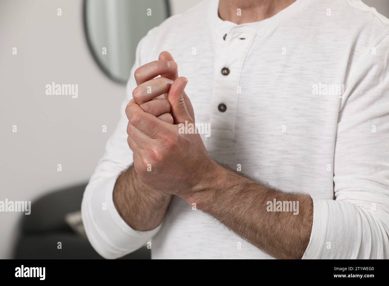 Man cracking his knuckles on blurred background, closeup. Bad habit