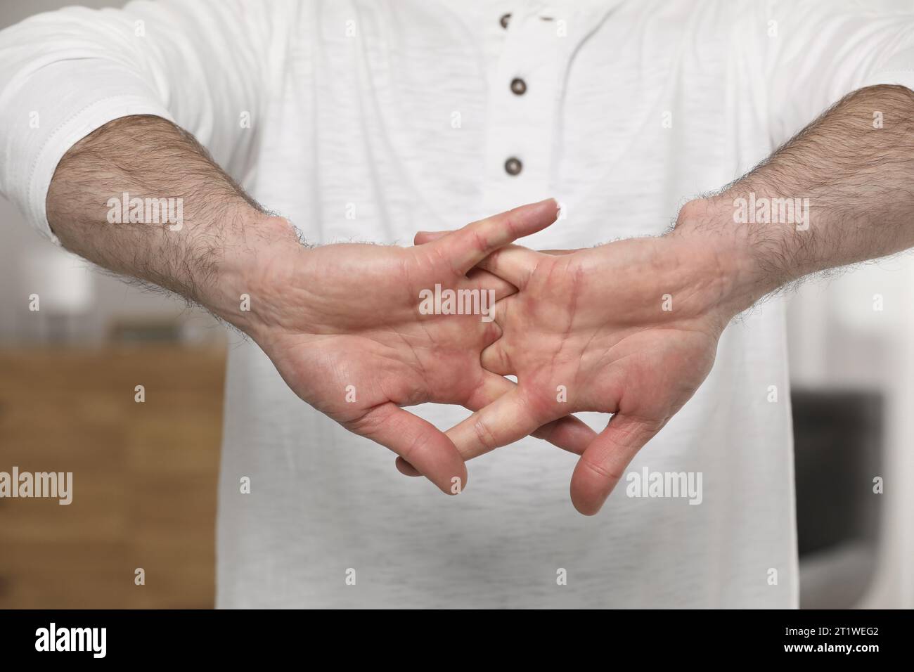 Man cracking his knuckles on blurred background, closeup. Bad habit