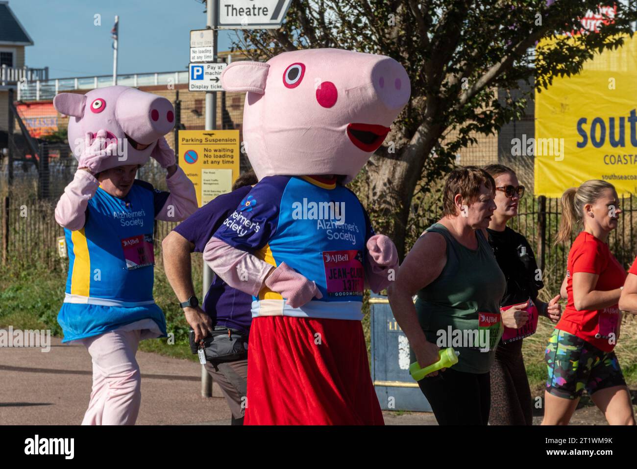 Great South Run, 15 October 2023, Portsmouth, Hampshire, England, UK. Thousands of competitors ran in the 10 mile Great South Run starting and ending in Southsea, Portsmouth.  As well as the elite runners, many other people took part running for charity or for their clubs. Pictured: two runners wearing Peppa Pig costumes raising money for the Alzheimers Society charity Stock Photo