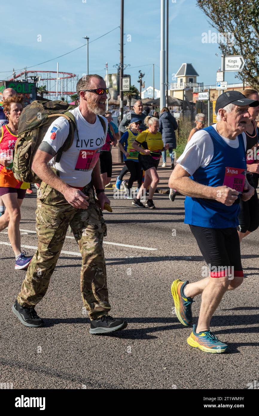 Great South Run, 15 October 2023, Portsmouth, Hampshire, England, UK. Thousands of competitors ran in the 10 mile Great South Run starting and ending in Southsea, Portsmouth.  As well as the elite runners, many other people took part running for charity or for their clubs.. Pictured: soldier running with a heavy backpack raising money for the Royal British Legion charity Stock Photo