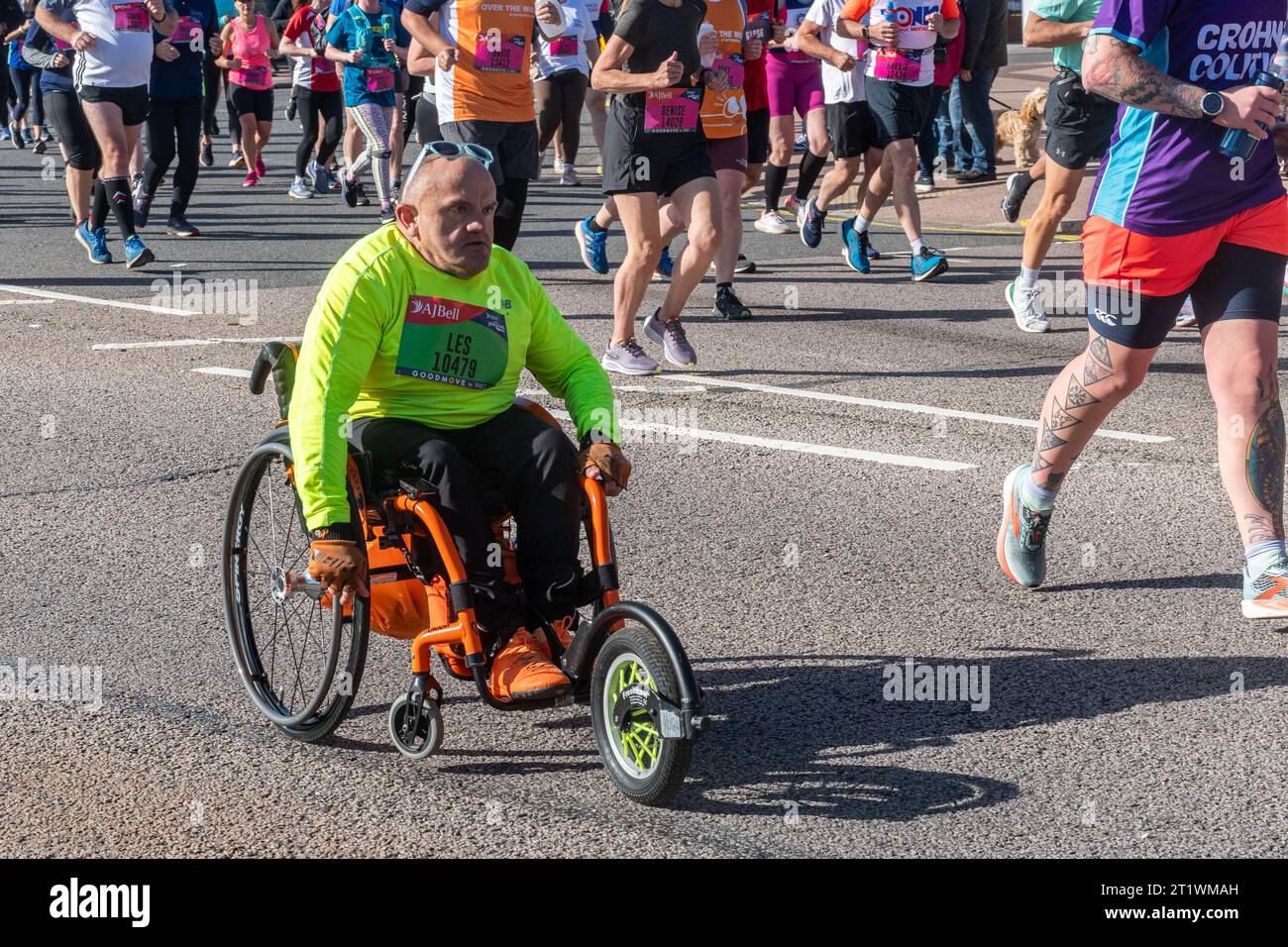 Great South Run, 15 October 2023, Portsmouth, Hampshire, England, UK. Thousands of competitors ran in the 10 mile Great South Run starting and ending in Southsea, Portsmouth.  As well as the elite runners, many other people took part running for charity or for their clubs. Pictured: a wheelchair competitor taking part in the event alongside lots of runners Stock Photo