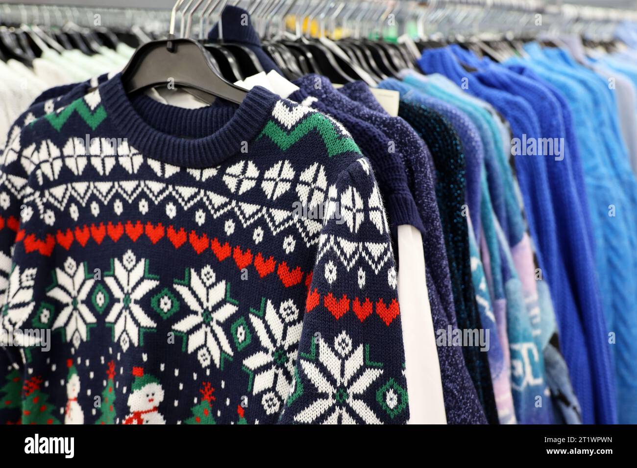 Knitted sweaters with winter pattern in a store. Traditional warm outfit for New Year holidays Stock Photo