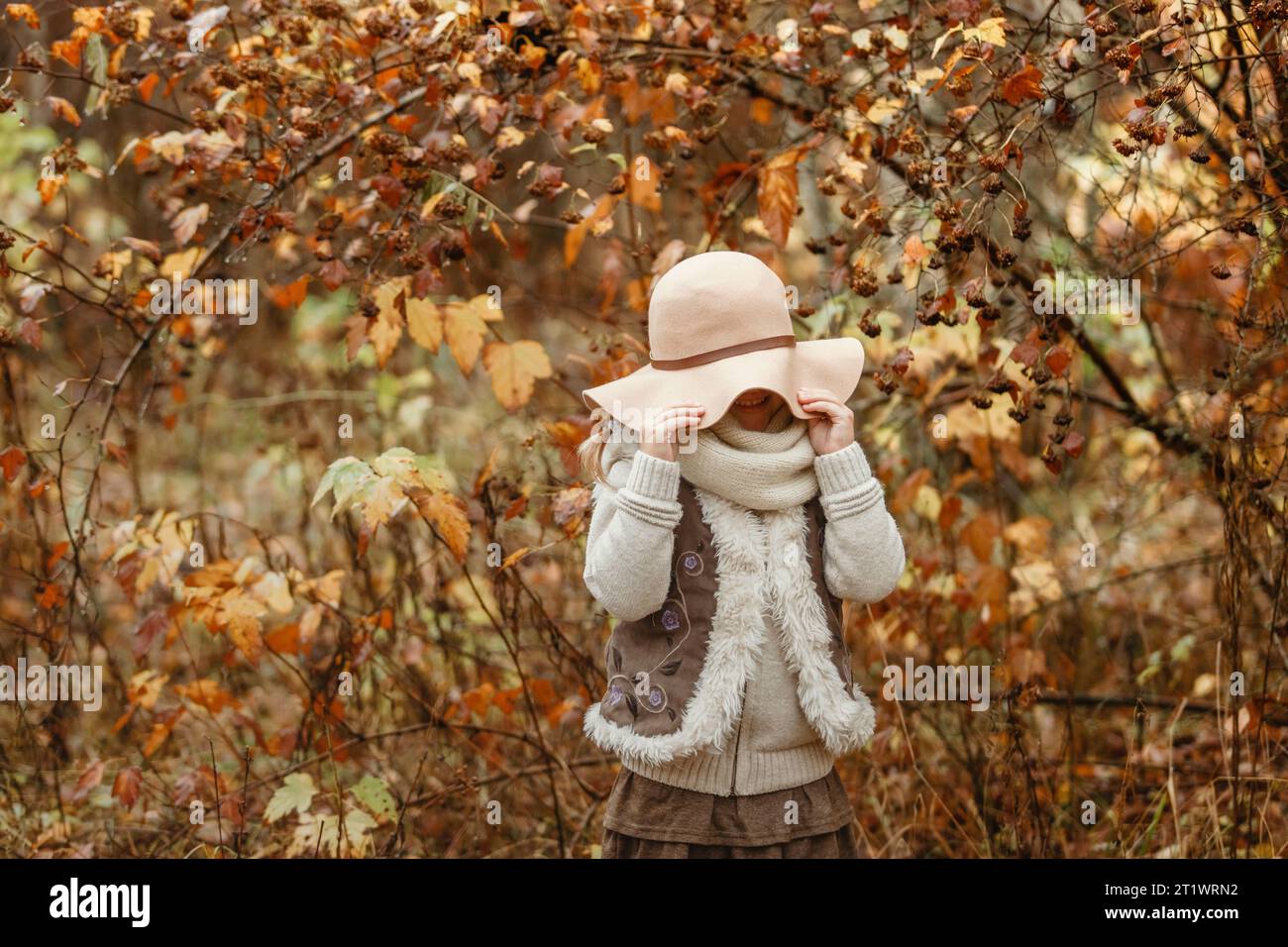 Portrait of a smiling young girl in a hat in an autumn park. She ...