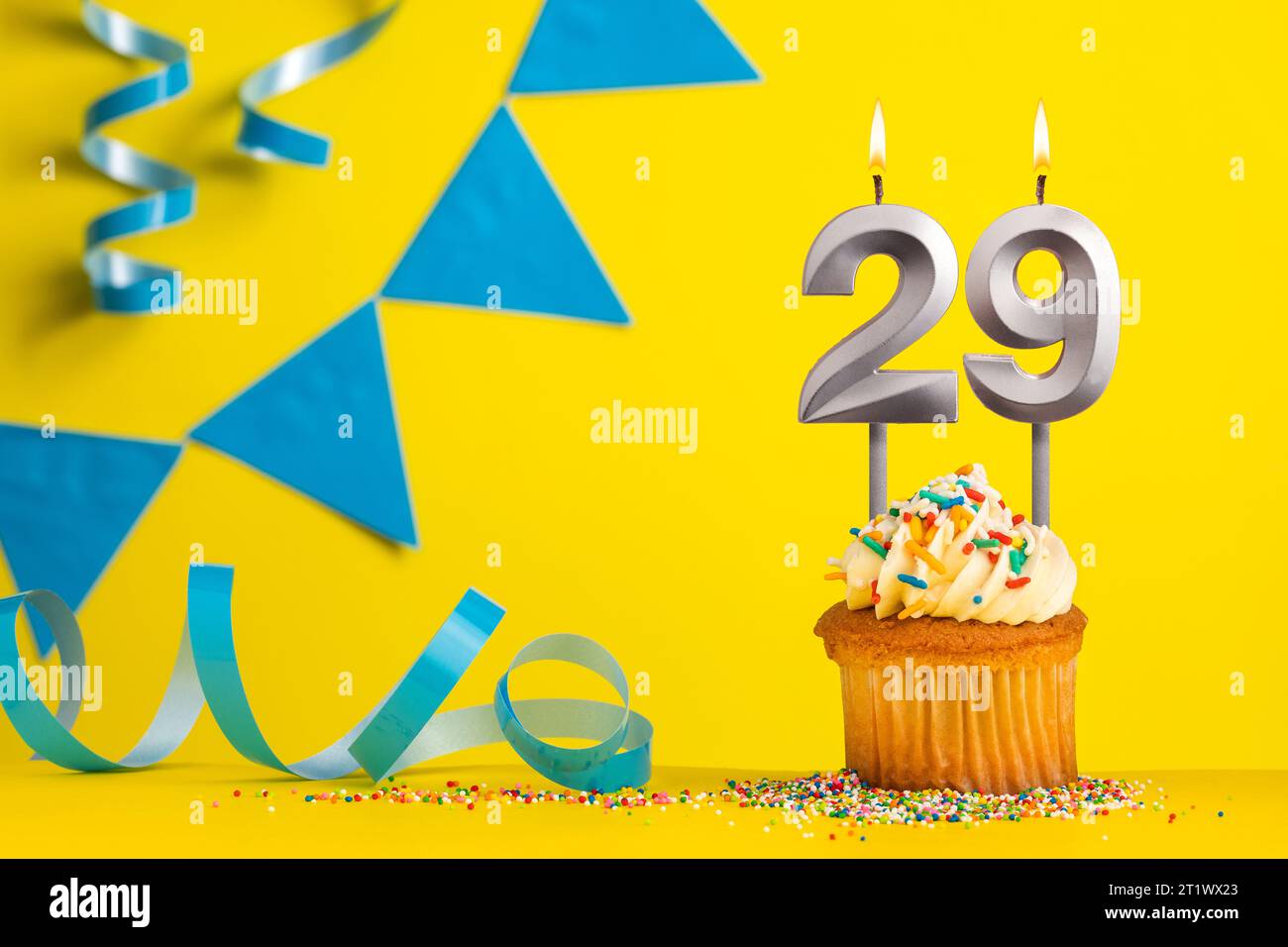 Birthday candle number 29 with cupcake - Yellow background with blue pennants Stock Photo