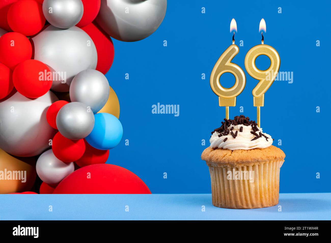 Cupcake with sparkling candle for 39th birthday or anniversary with big  number in white with yellow streamers on blue table with dark background  full Stock Photo - Alamy
