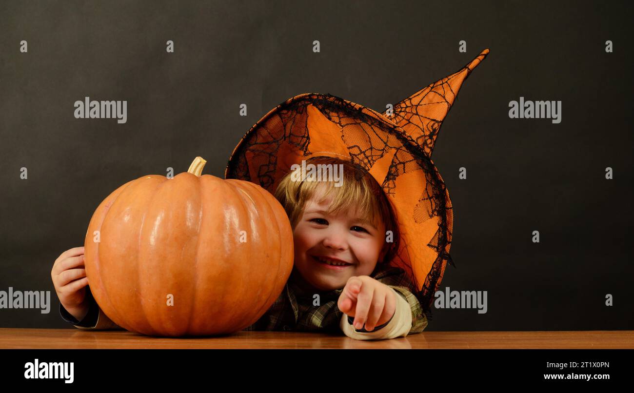 Halloween holidays. Little kid wizard with Jack-o-lantern preparing for Halloween. Trick or treat. Happy child boy in witch hat with Halloween pumpkin Stock Photo