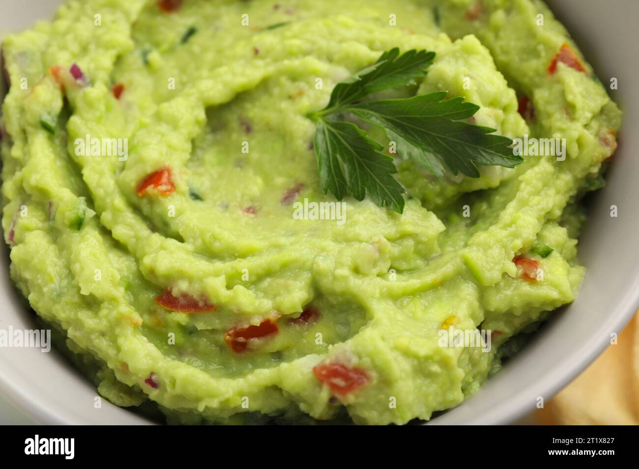 Bowl of delicious guacamole with parsley, closeup Stock Photo