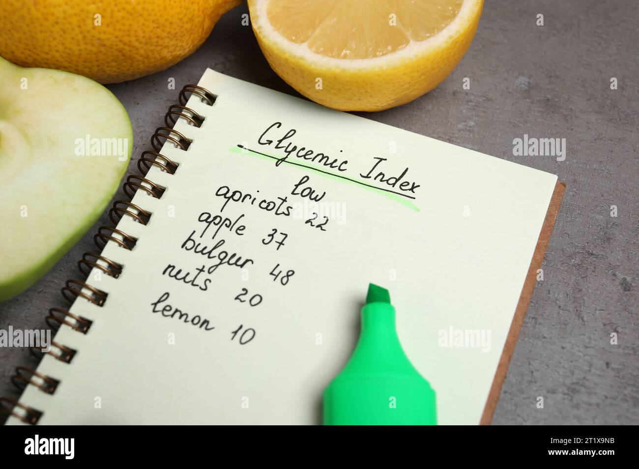 Notebook with products of low glycemic index, marker and fruits on grey table, closeup Stock Photo