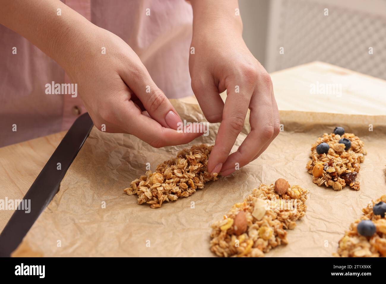 Making granola bars. Woman putting mixture of oat flakes, dry fruits