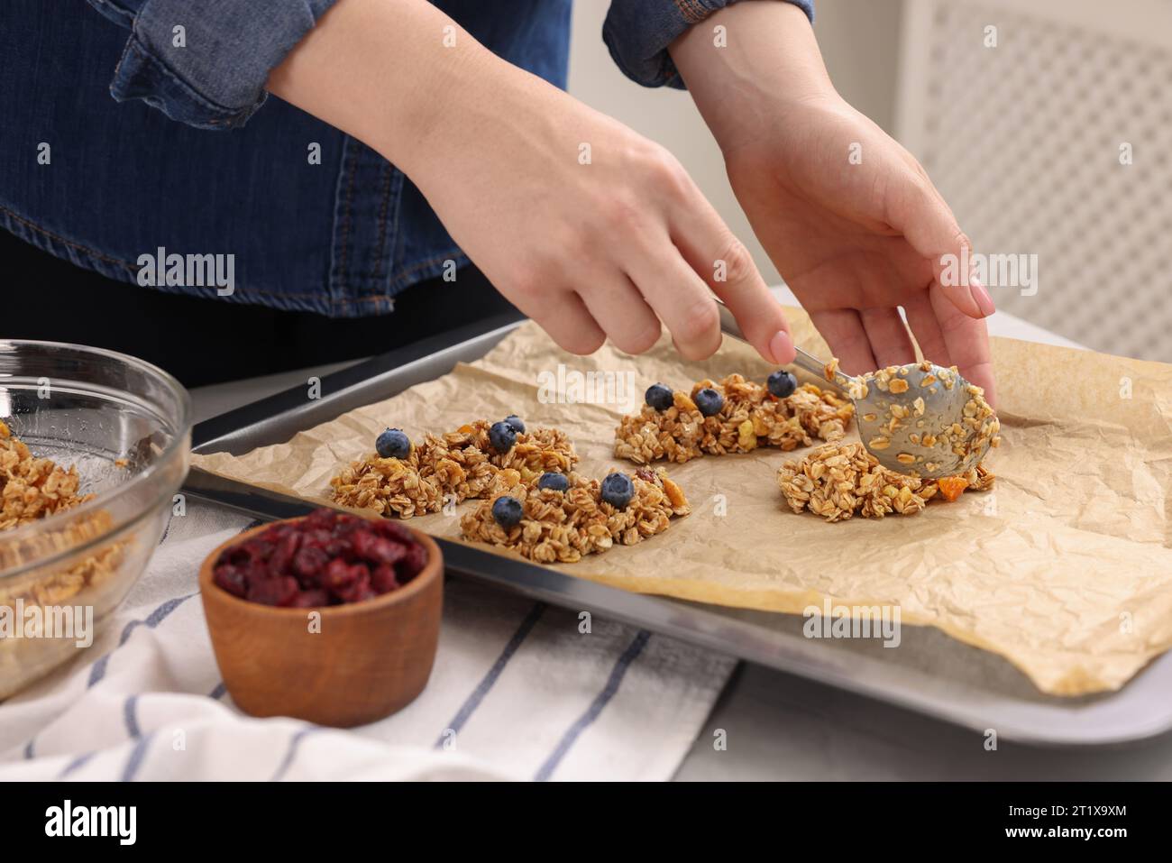 Making granola bars. Woman putting mixture of oat flakes, dry fruits
