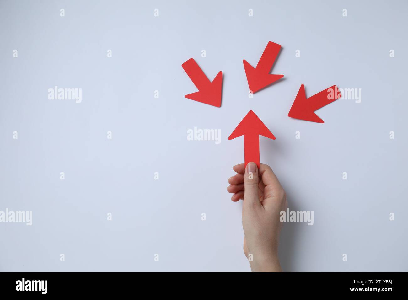 Woman holding red paper arrow and other arrows pointing at it on white ...