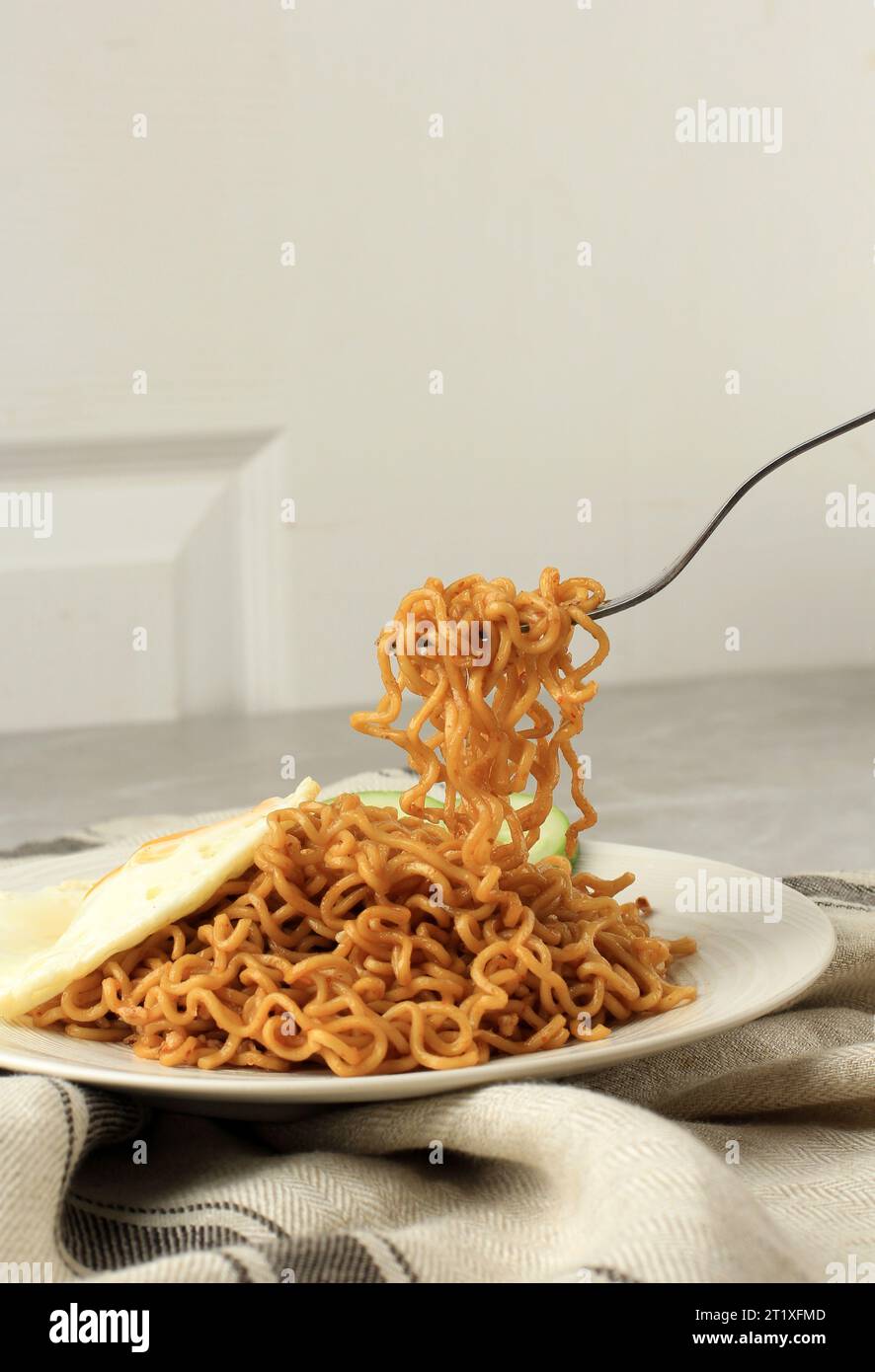 Eat Fried Noodle Indomie Goreng, Take Noodles with Fork. Indonesian