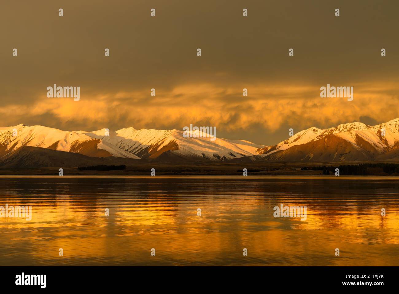 Vibrant sky colour and stunning reflections on lake tekapo as nightfall  closes in Stock Photo