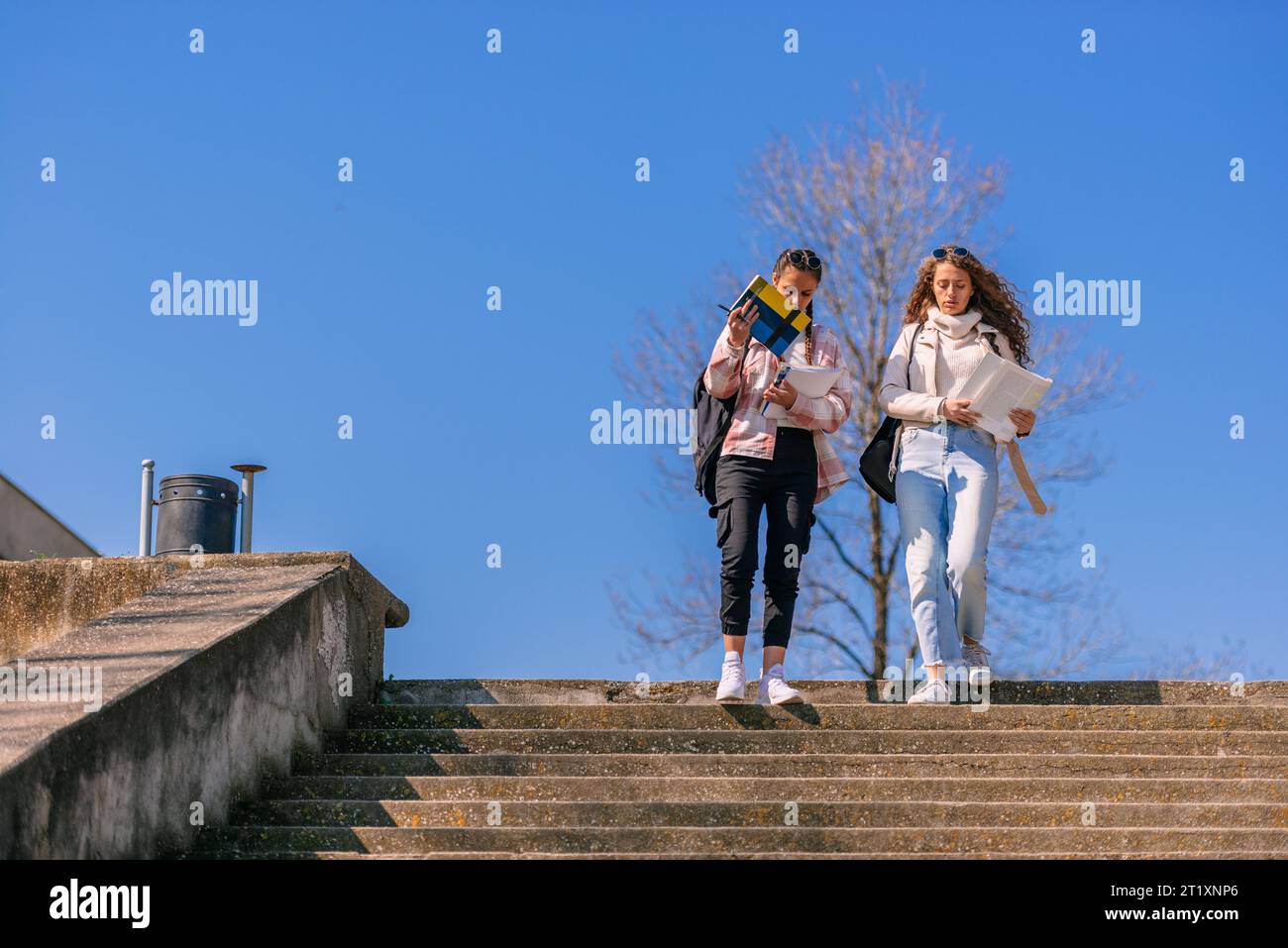High school girls reading books and walking downstairs Stock Photo - Alamy