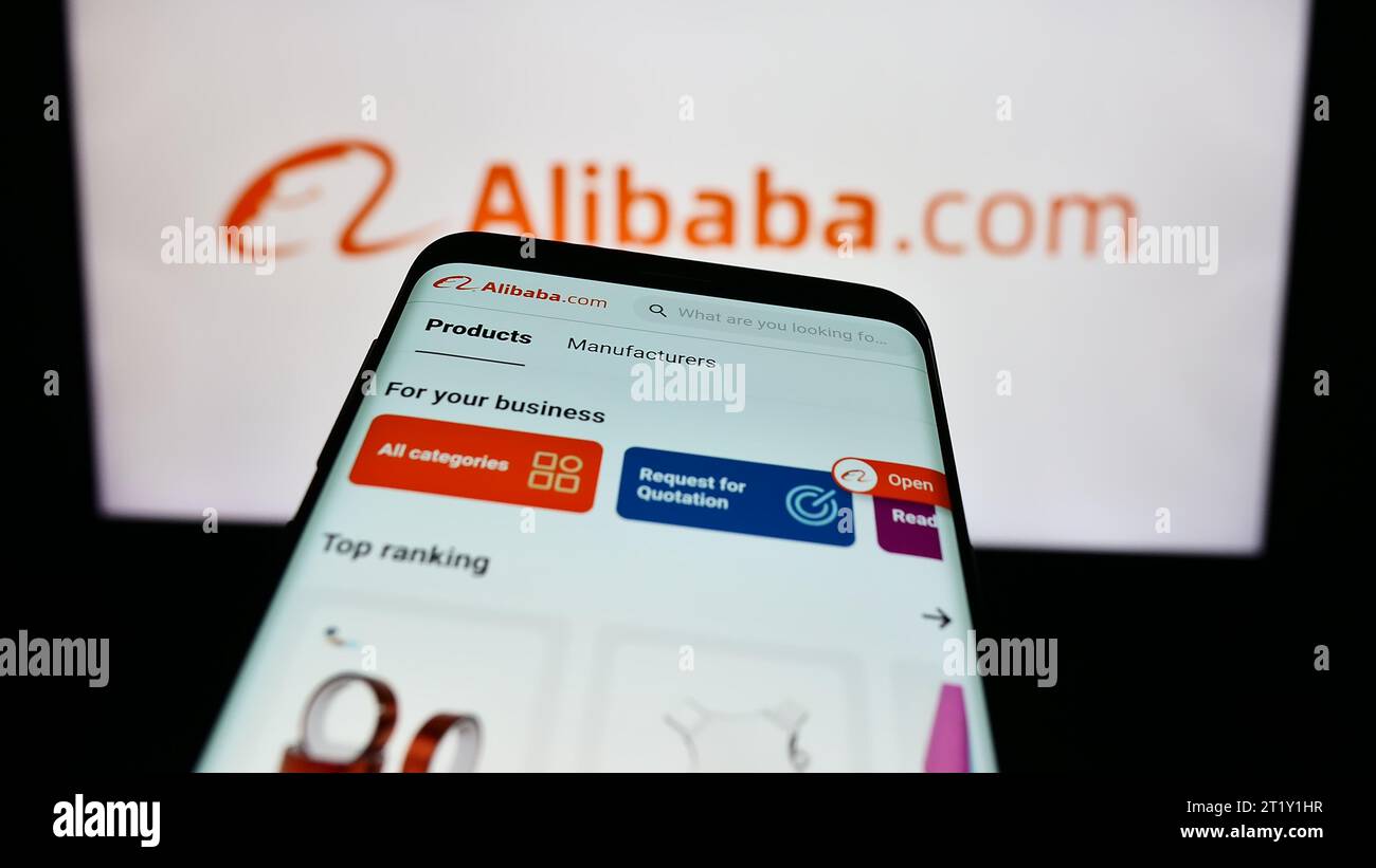 Mobile phone with webpage of Chinese B2B e-commerce platform Alibaba.com in front of business logo. Focus on top-left of phone display. Stock Photo