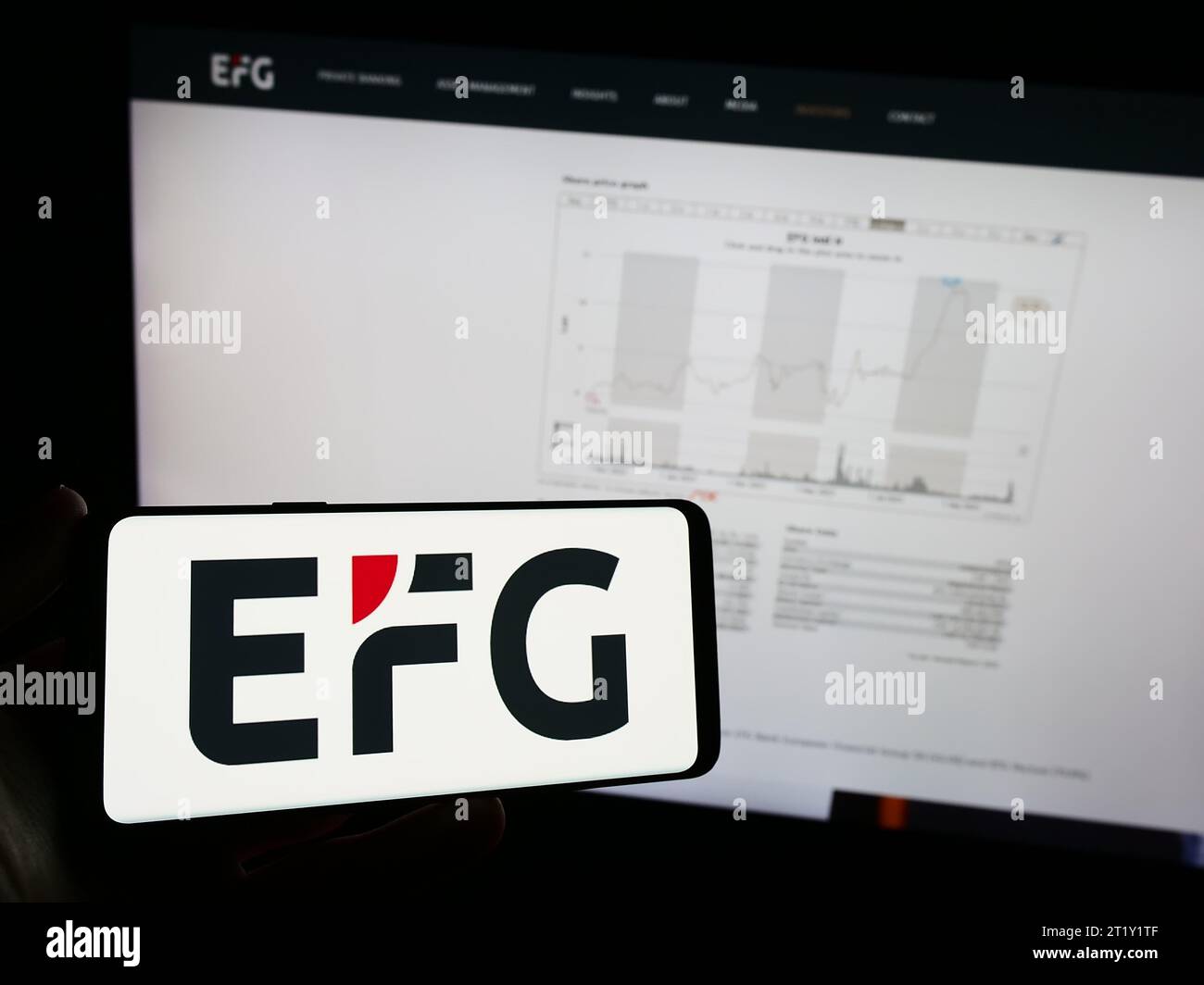 Person holding mobile phone with logo of Swiss private bank company EFG