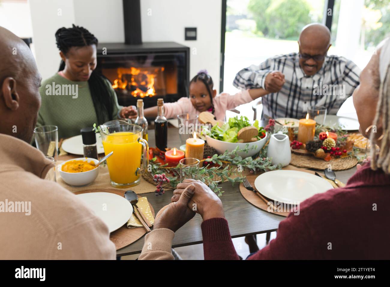 Happy african american multi generation family holding hands at thanksgiving dinner Stock Photo