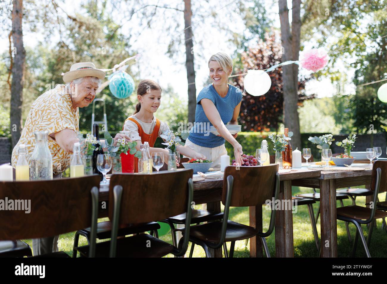 Grandmother, mother and daughter setting table for summer garden party ...