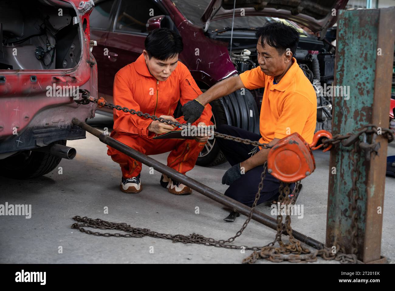 Mechanic testing strength and reliability of chain hoist for car towing