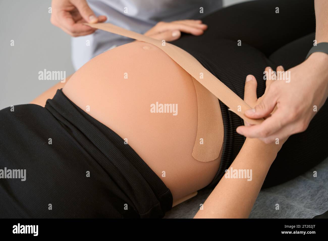 Specialist kinesiotherapist taps the belly of a pregnant woman Stock Photo