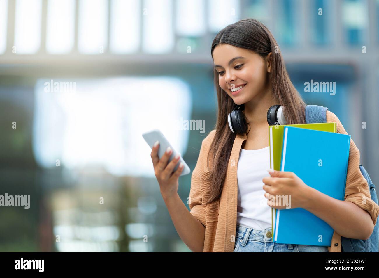 Smiling student using app on smartphone, campus Stock Photo