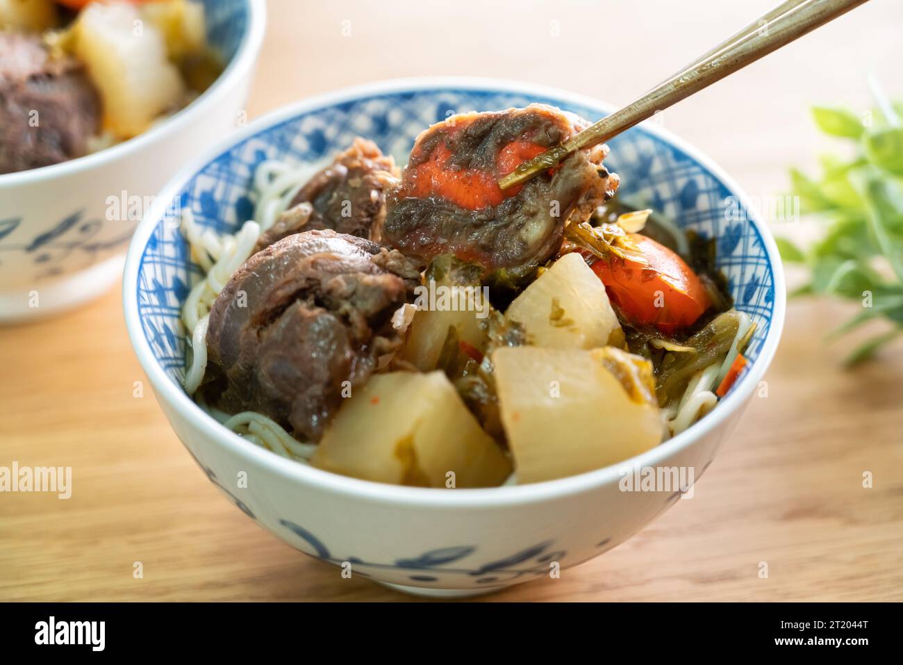 Beef noodle soup. Taiwanese famous food with sliced red braised beef and vegetables in a bowl on wooden table background. Stock Photo