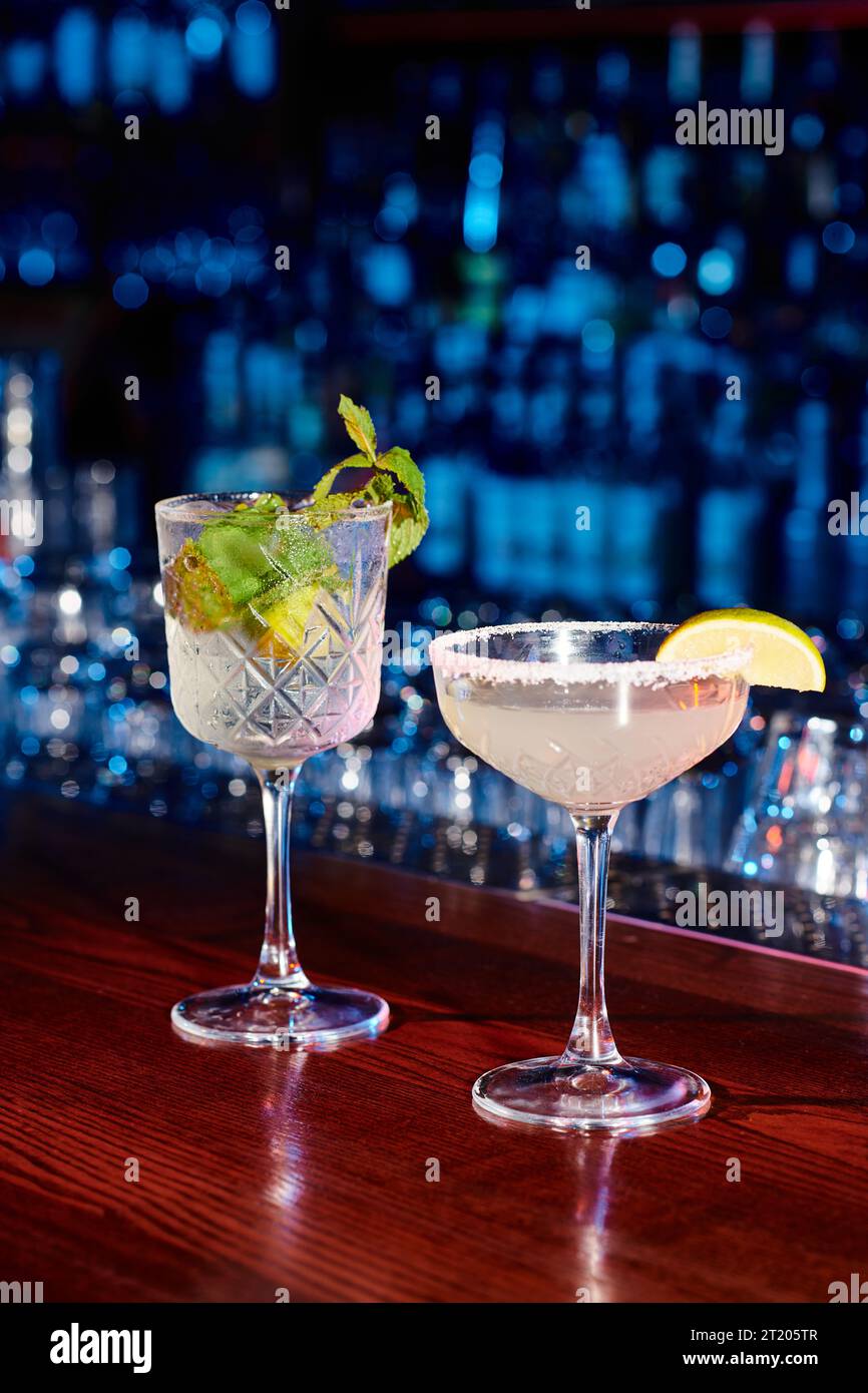 elegant glasses of tasty cocktails with garnishments with bar on backdrop, concept Stock Photo