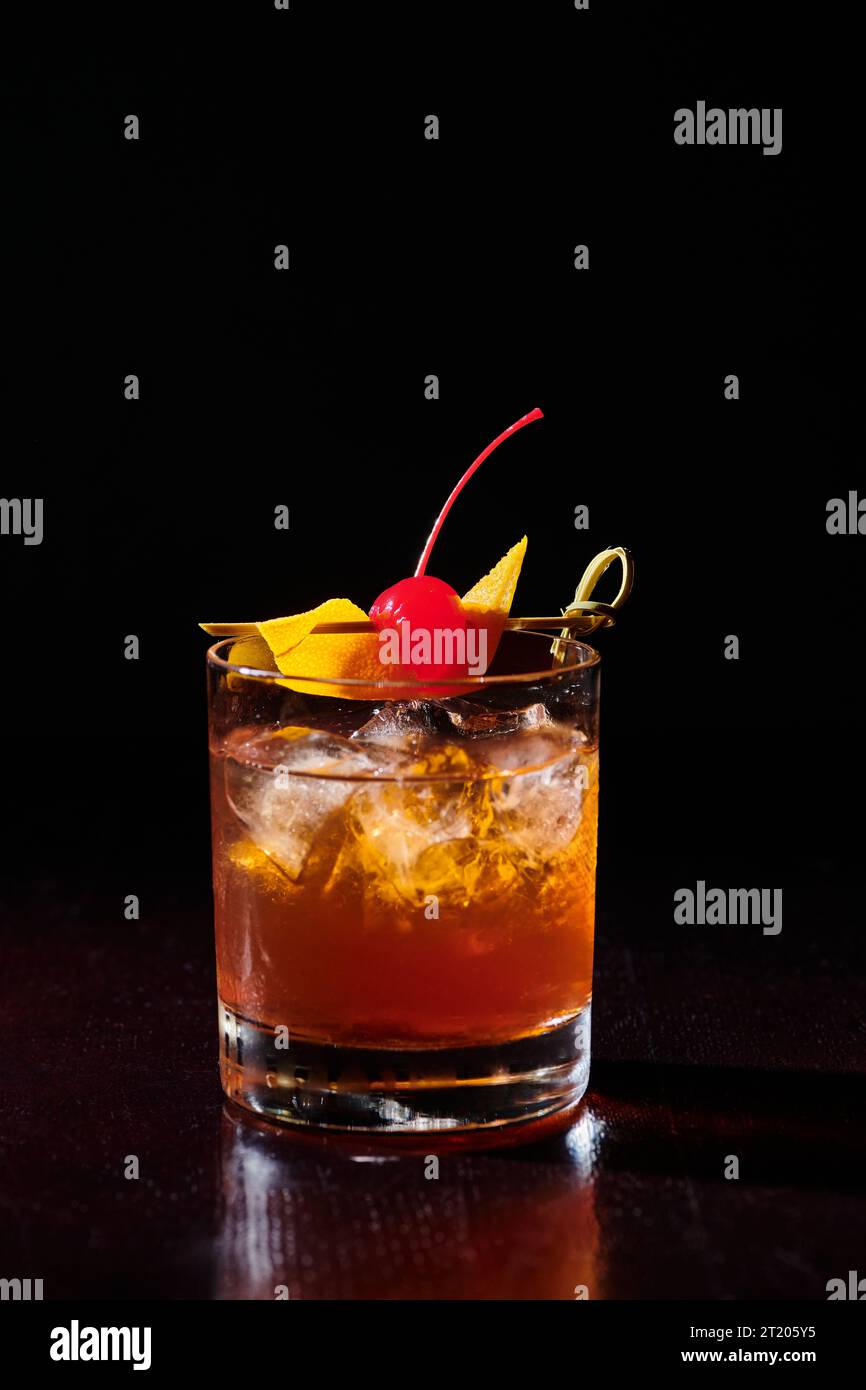 ice cold intense negroni garnished with cocktail cherry on black