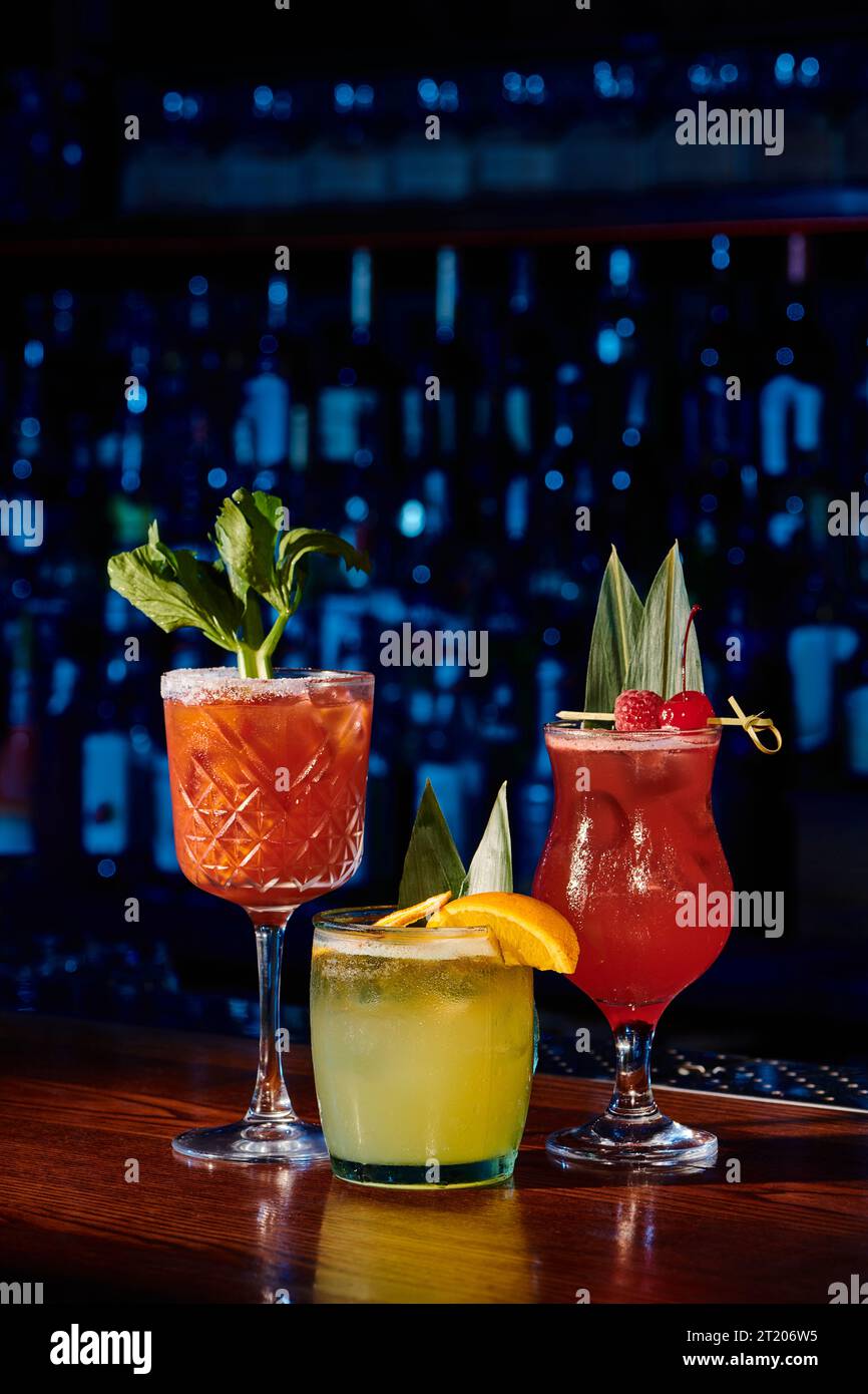 three refreshing cocktails with fruit and plant decorations with bar on background, concept Stock Photo