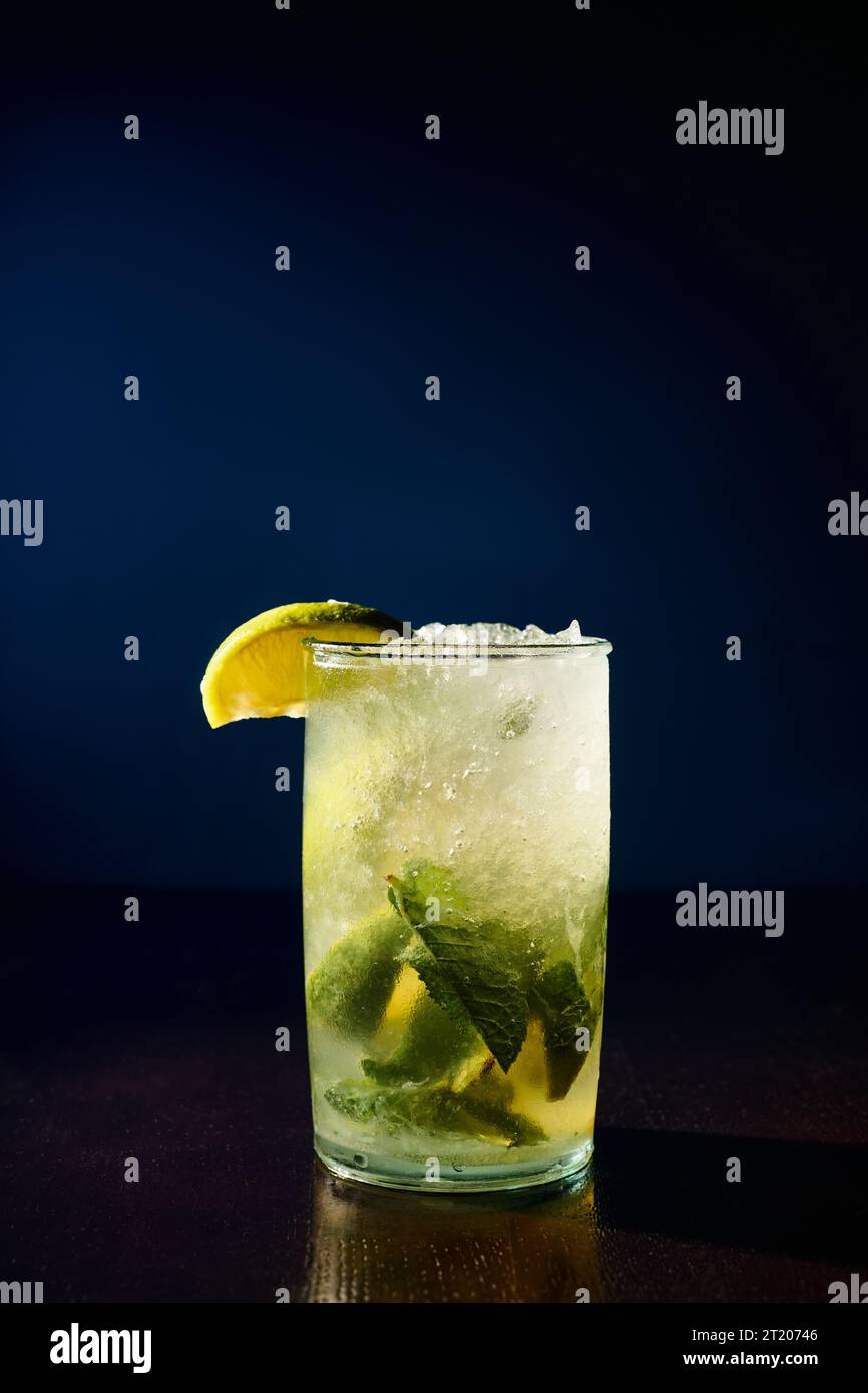 freshening glass of mojito garnished with mint and lime slices on dark background, concept Stock Photo