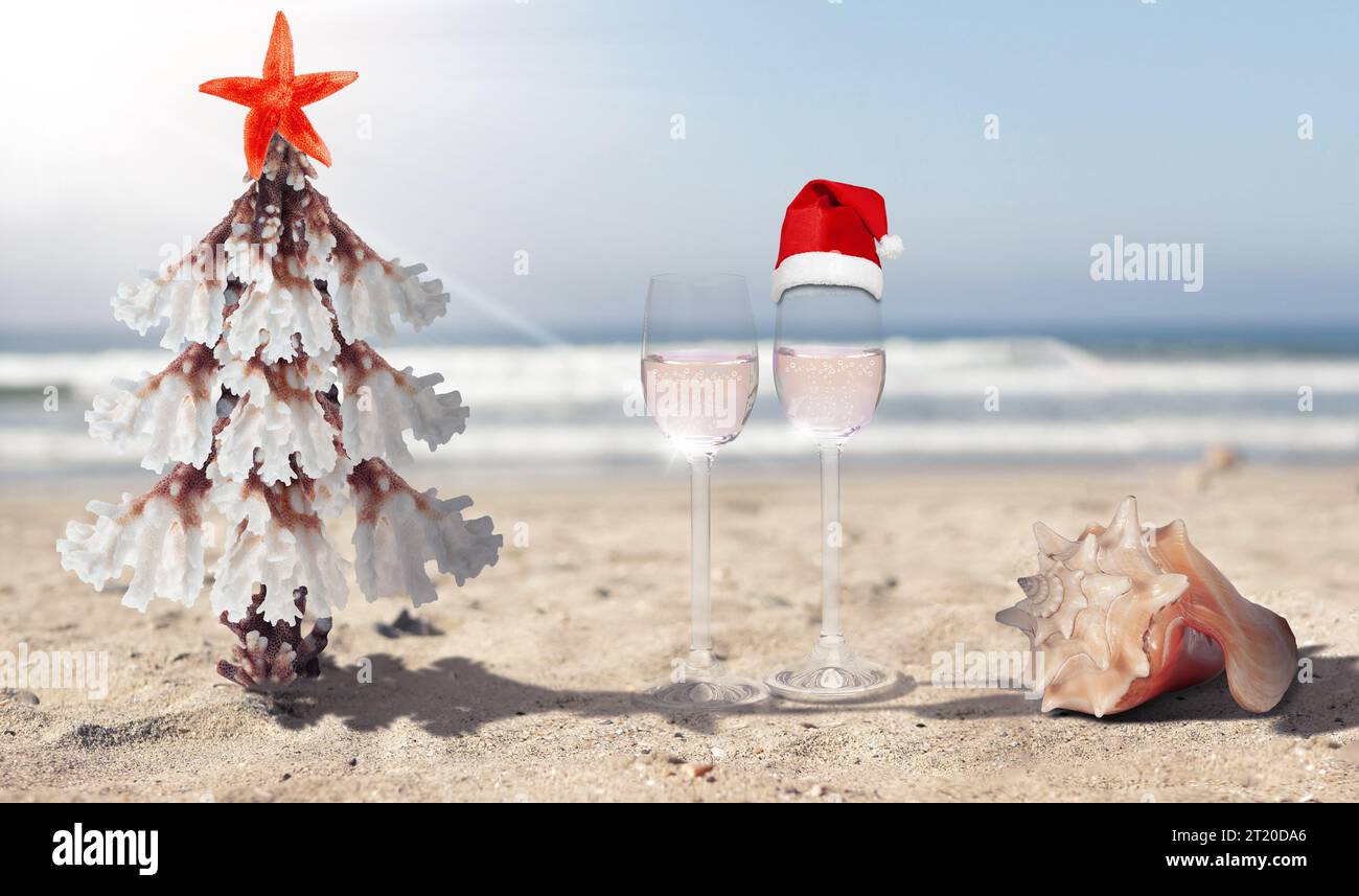 Concept of Christmas and New Year celebrations in tropical countries. Stylised Christmas tree made of coral and starfish, shells and wine glasses Stock Photo