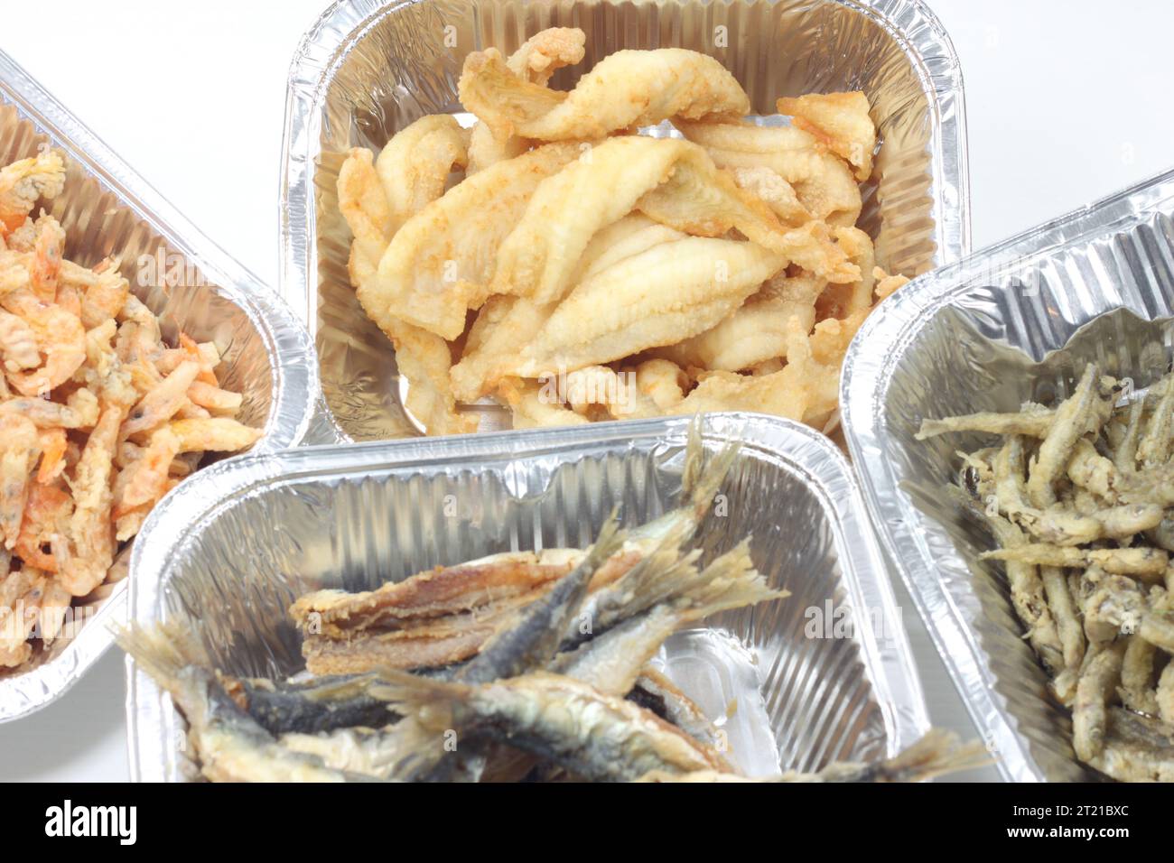 A closeup of fish in tinfoil containers on a white background Stock Photo