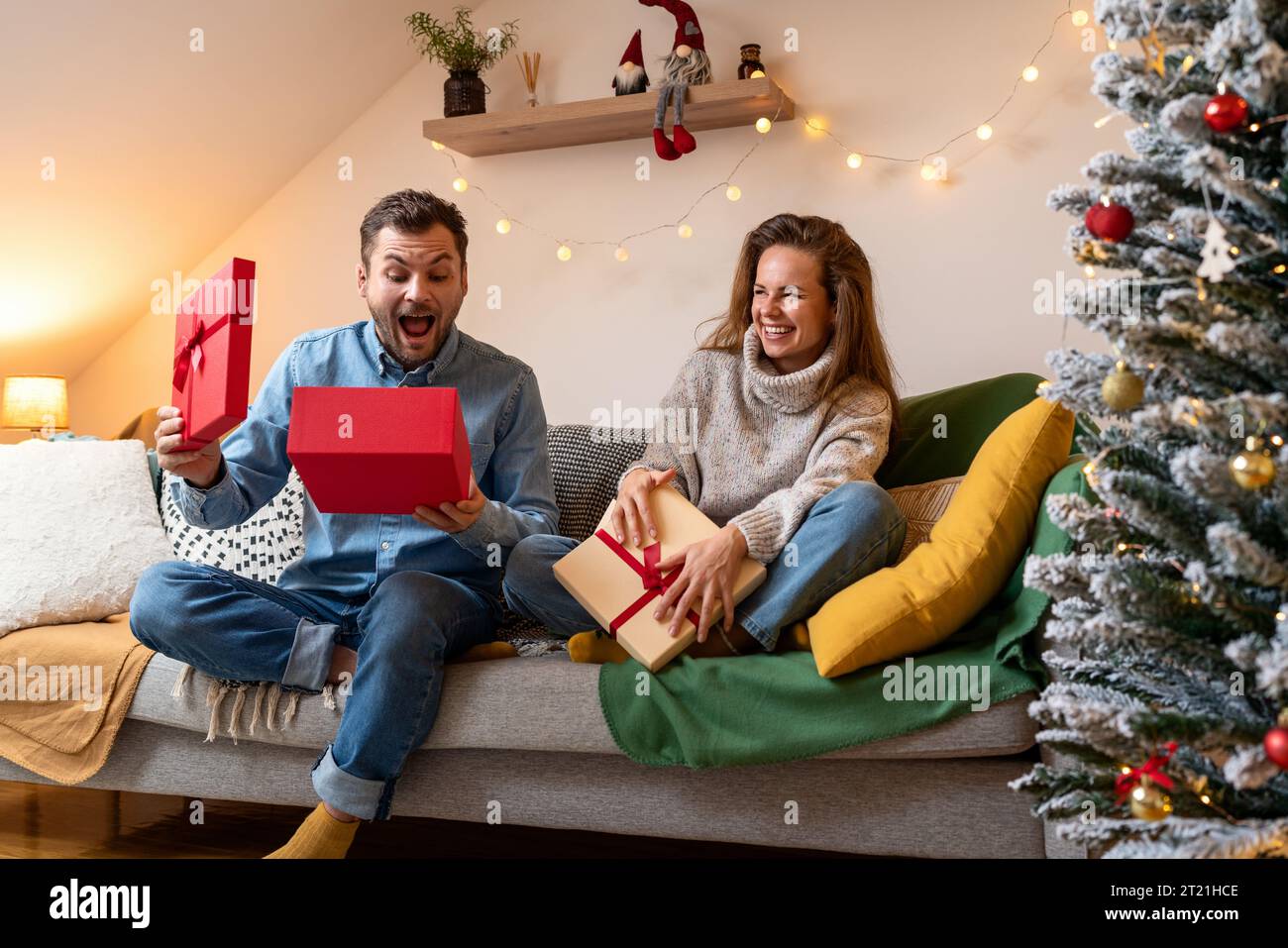 Christmas surprise and giving gifts. Happy married typing couple and Christmas presents. Stock Photo