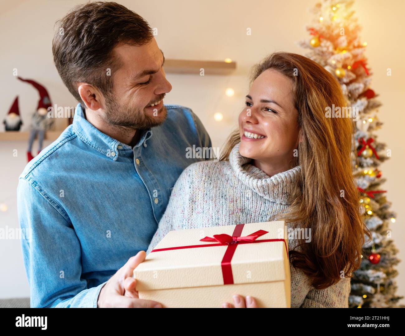Happy heterosexual couple and Christmas presents. Boyfriend gives xmas gift to girlfriend. Season of giving. Stock Photo