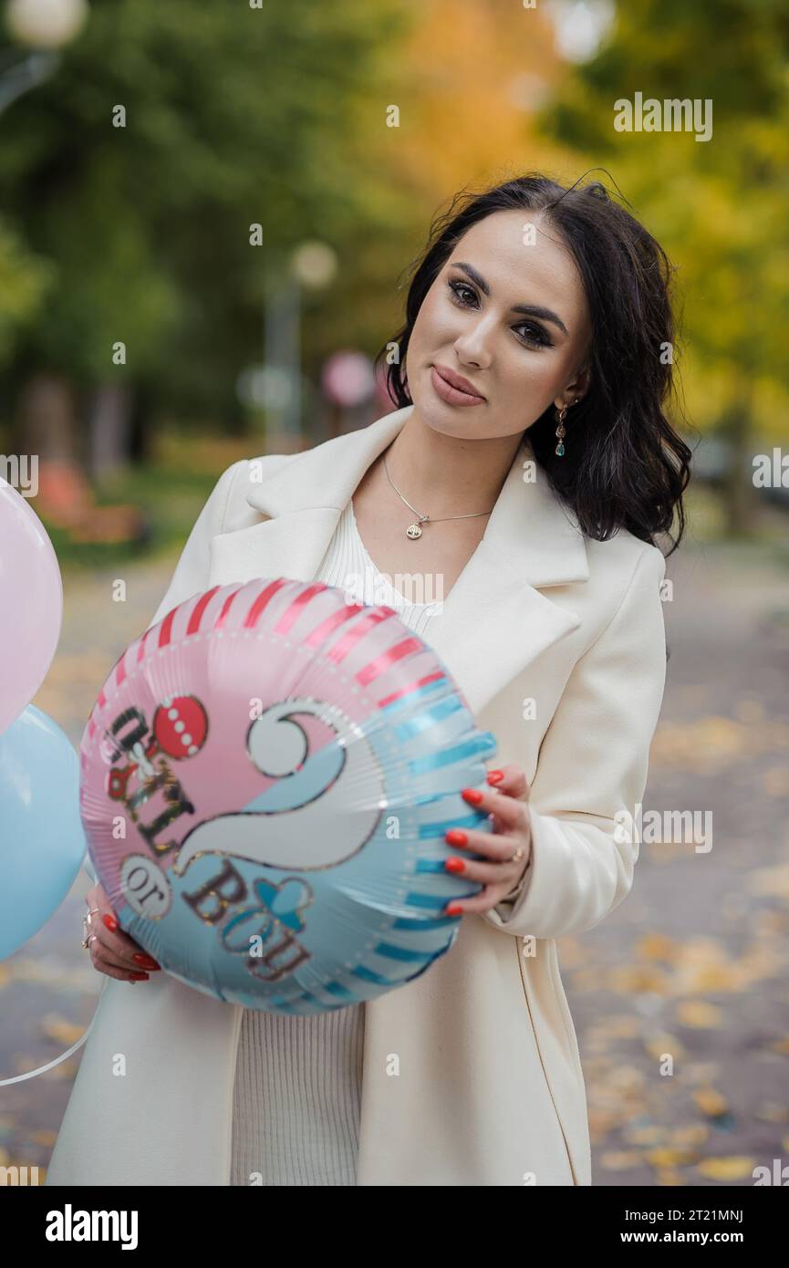Beautiful pregnant woman holding blue and pink inflatable balloons. Inflatable balloons that allow you to find out the gender of your unborn child. Ge Stock Photo